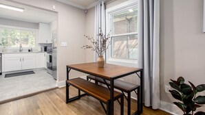 Una cocina moderna con armarios blancos, una mesa de comedor de madera y un banco.