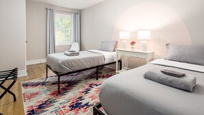 Un dormitorio con dos camas, un escritorio con lámpara y un tapete colorido.