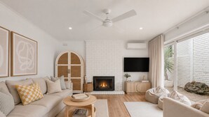A modern living room with a fireplace, a sofa, a coffee table, and a TV mounted on the wall. - Boutique Retreat Portsea by Ready Set Stay (Portsea)