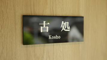 A sign with Japanese characters and the English word "Kosho" on a wooden wall.