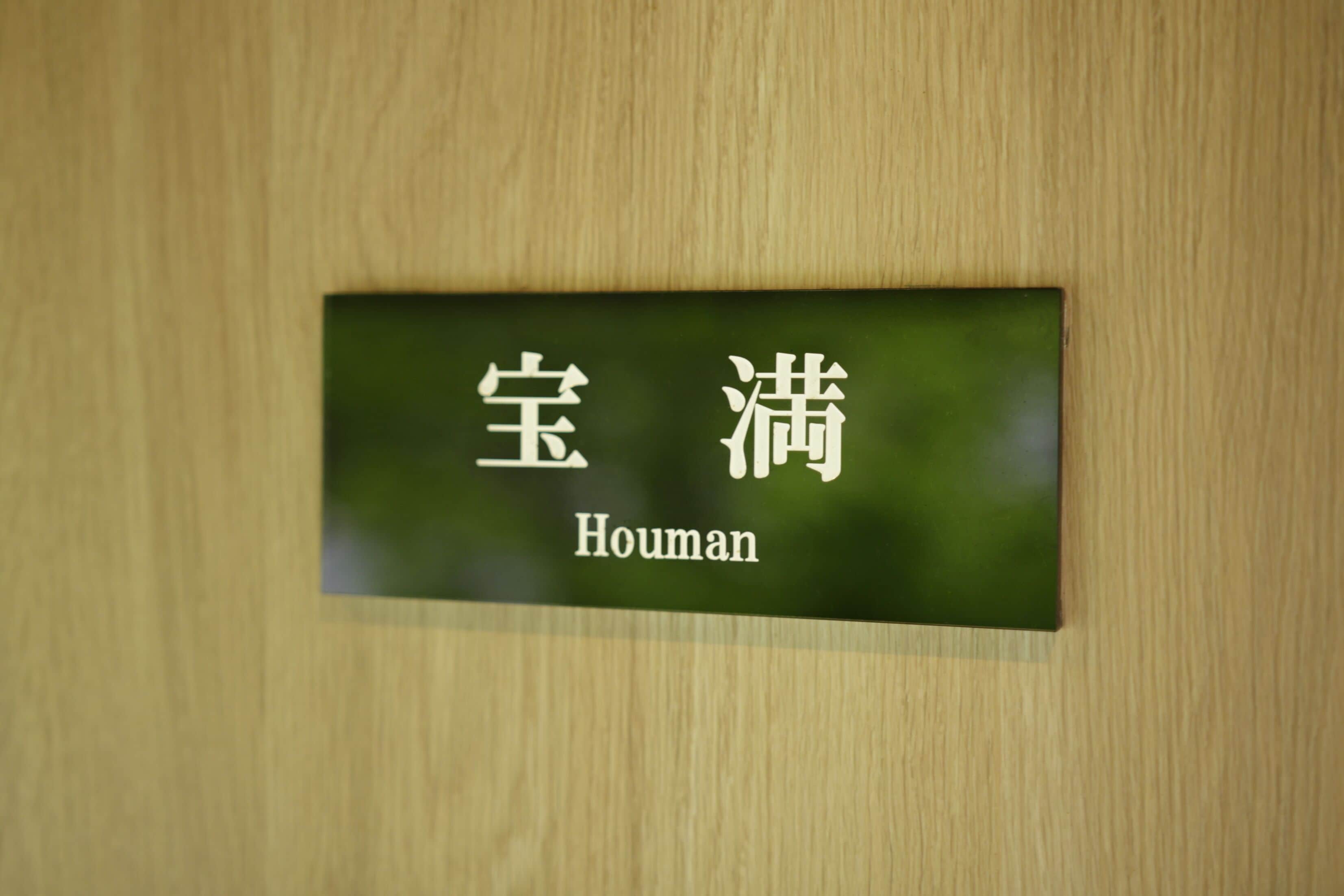 Uma porta de madeira com uma placa que diz 'Houman' em chinês e inglês.