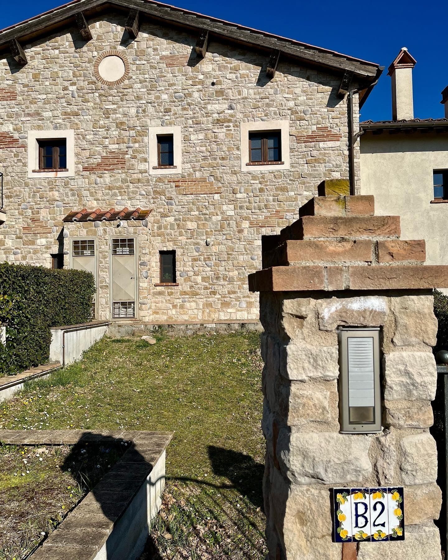 A stone building with a tiled roof, a small garden, and a mailbox labeled "B2".