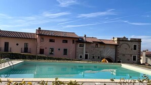 Ein Schwimmbad mit einem Steinhaus im Hintergrund.