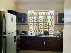 Una cocina equipada con refrigerador, microondas, pileta y alacenas.