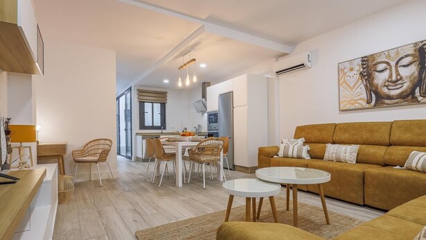 Un salon moderne avec un canapé, une table à manger et une cuisine en arrière-plan.