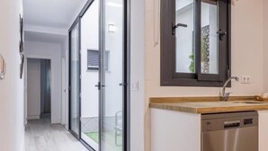 Une cuisine moderne équipée d’un lave-vaisselle, d’un évier avec un plan de travail en bois et d’une grande fenêtre située au-dessus de l’évier.