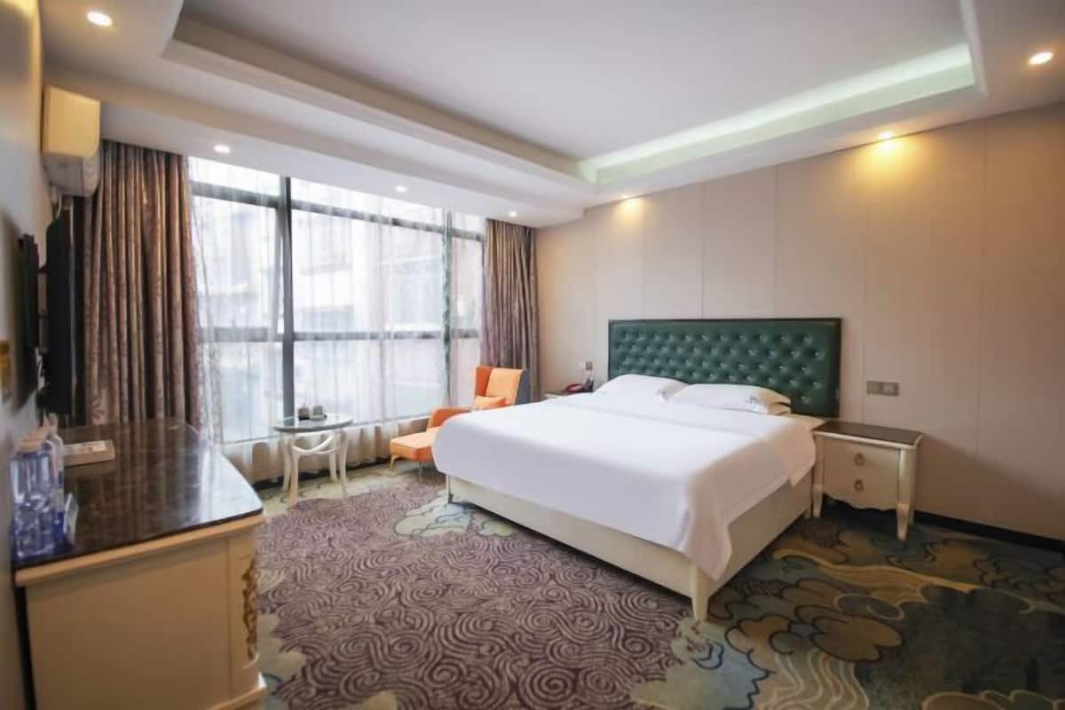 Ein Hotelzimmer mit einem großen Bett, einem Schreibtisch, einem Sessel und einem kleinen Tisch.