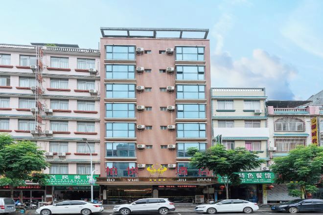 A multi-story hotel with a central entrance, multiple balconies, and signage for various businesses.