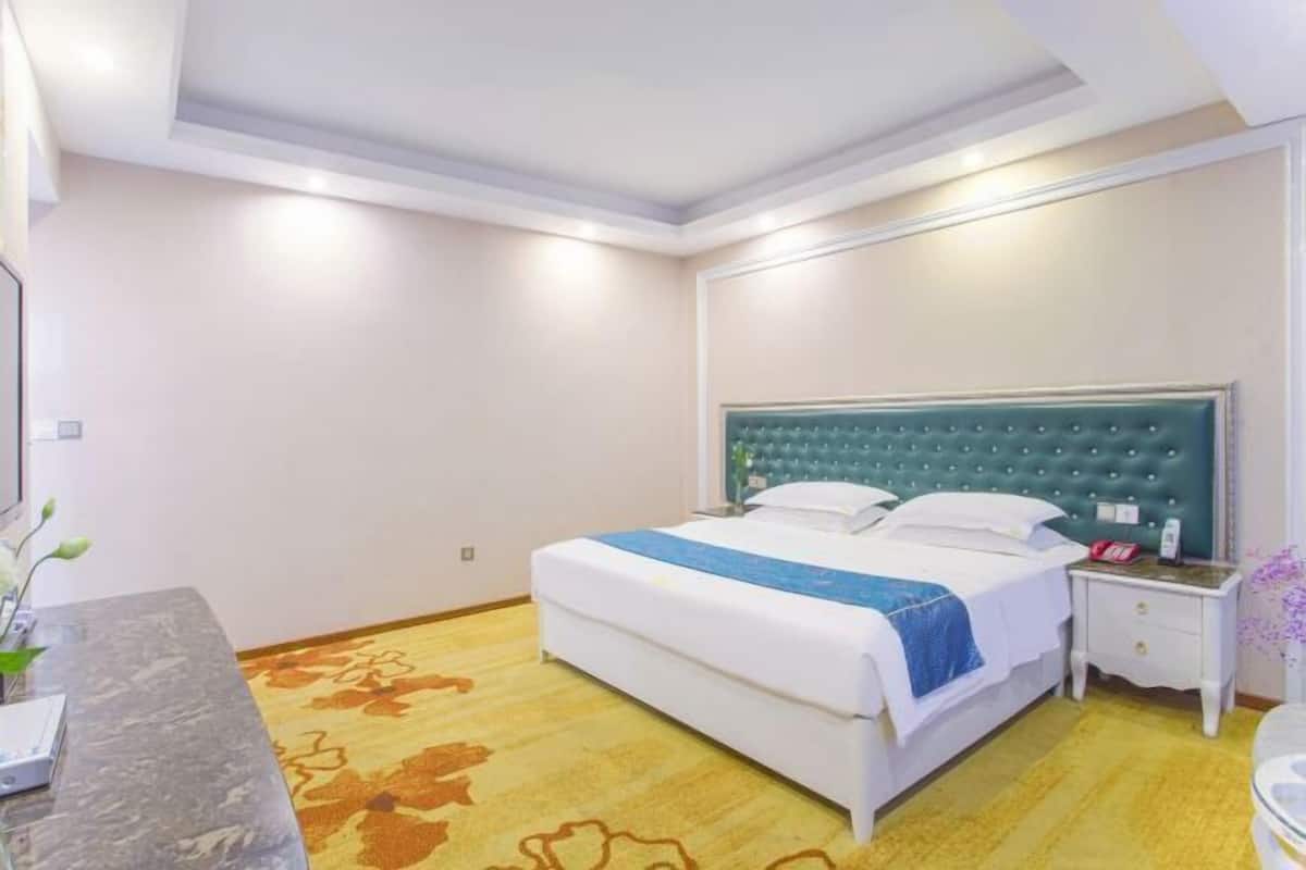Ein Hotelzimmer mit Bett, Nachttisch und Beistelltisch.