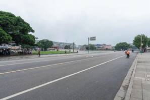 A wide road with a sidewalk on one side and a grassy area with trees on the other. - Bo Yue Hotel (Zhongshan)