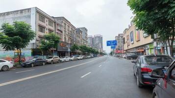 A street lined with parked cars and buildings, including a visible sign for a hotel.