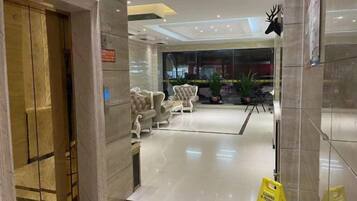 A hotel lobby with a reception desk, seating area, and a sign indicating a smoking area.
