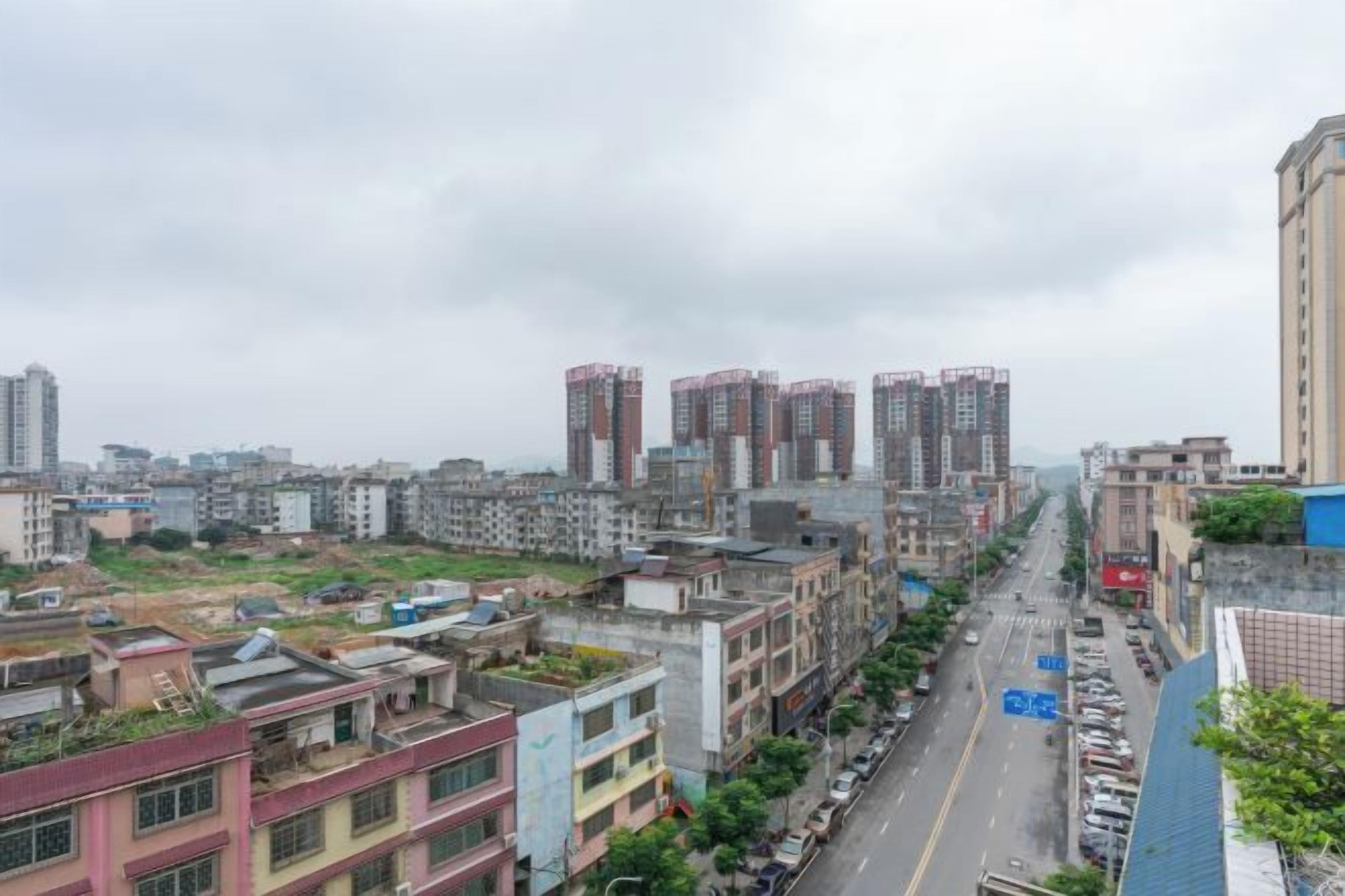 A cityscape with high-rise buildings, a road with vehicles, and a clear sky.