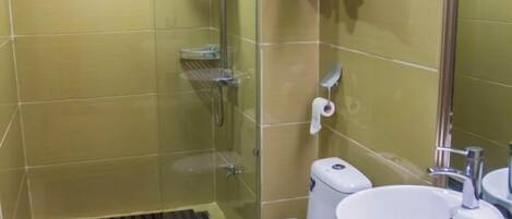A bathroom with a glass-enclosed shower, a toilet, and a sink.