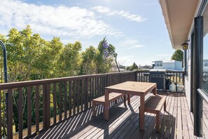 Eine Holzterrasse mit Tisch und Stühlen, mit Blick auf ein Wohngebiet mit Häusern und Bäumen.