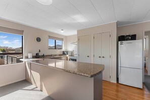 Una cocina moderna con una isla central, microondas integrado y refrigerador.