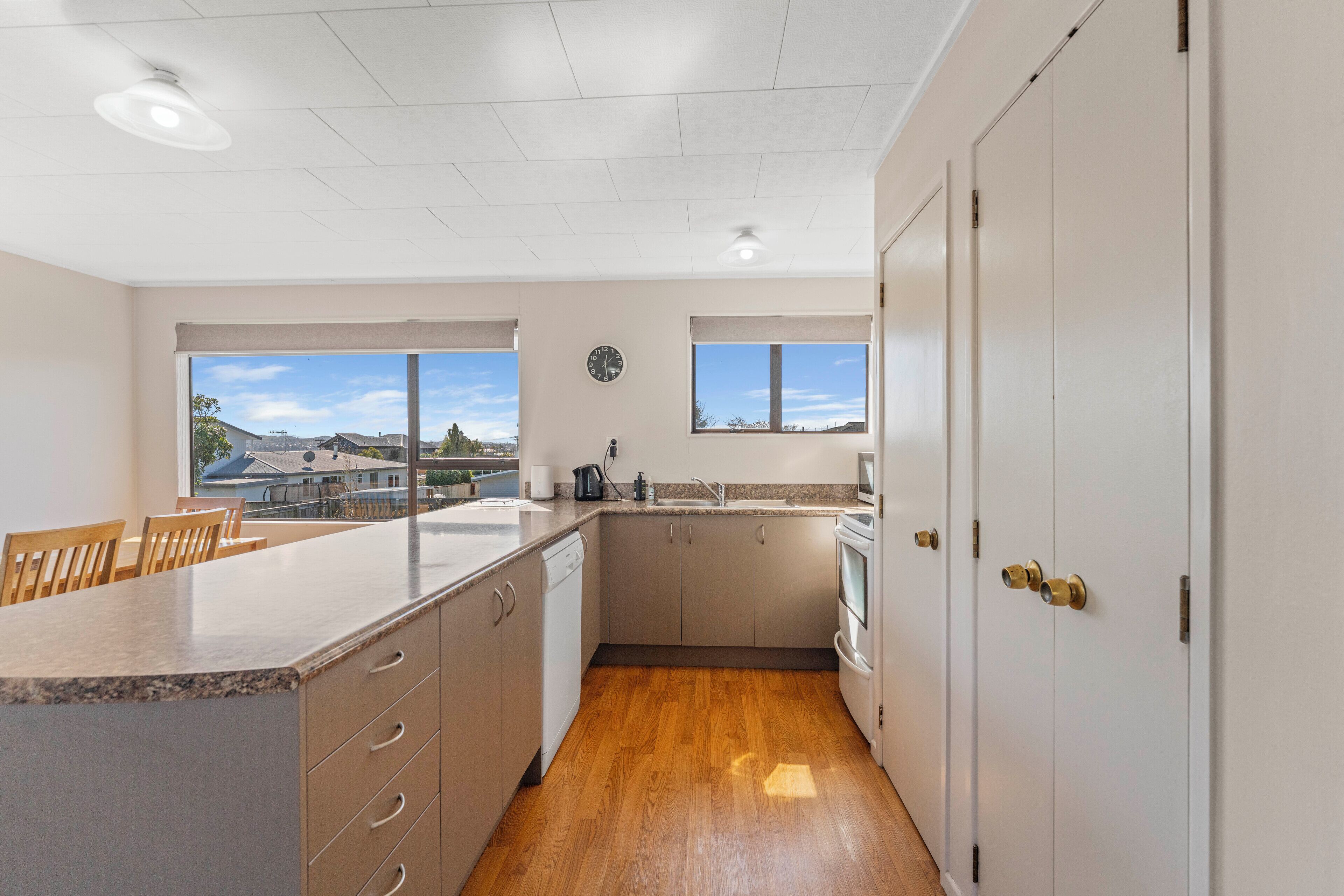 A kitchen with a wooden countertop, a dishwasher, a sink, and a window with a view of houses.