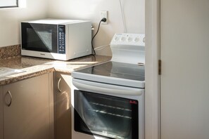 Eine Küche mit Mikrowelle, Herd, Backofen und einer Arbeitsplatte aus Granit.