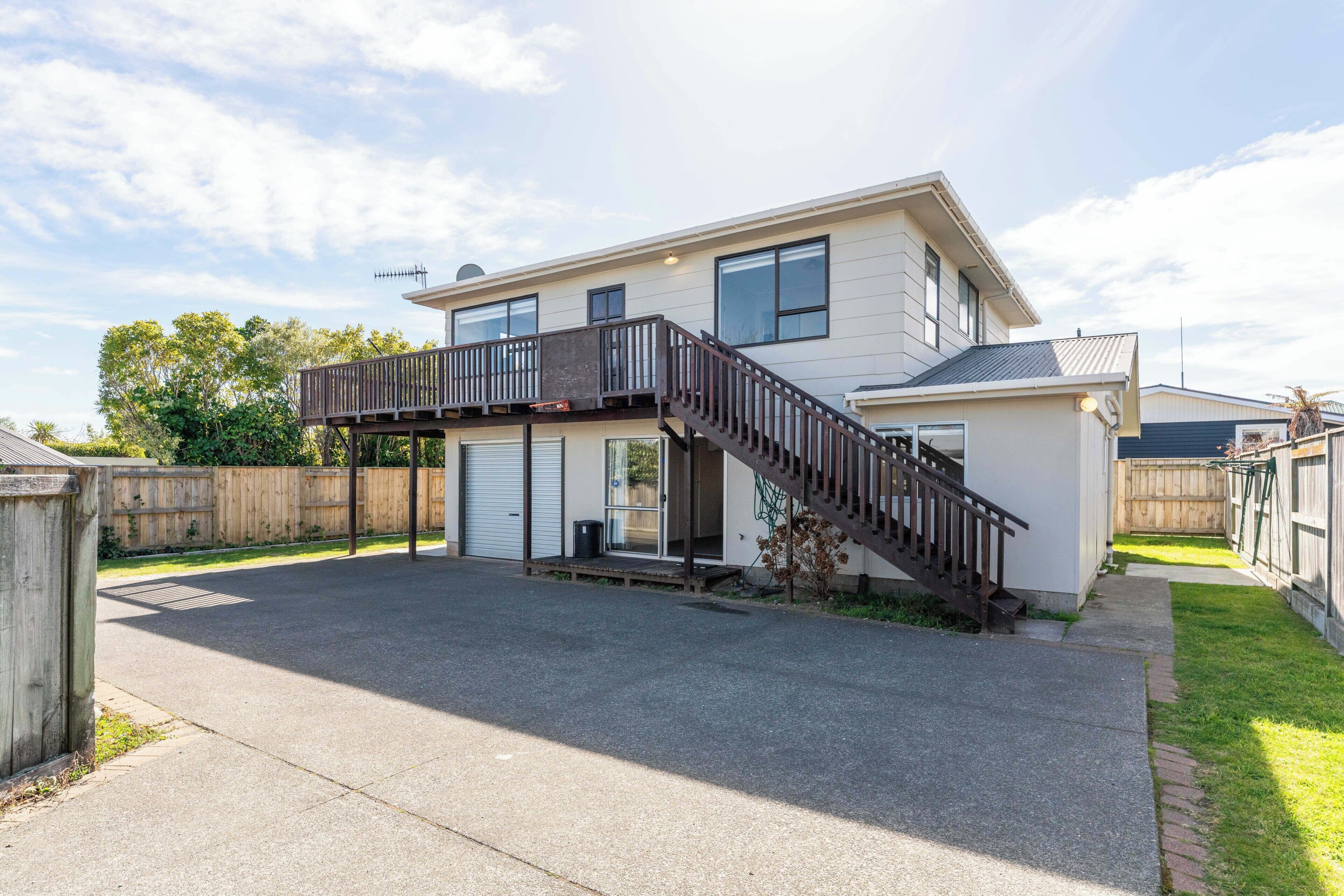 A two-story residential house with a front deck, a garage, and a small attached garage.