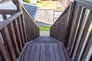 Eine Holztreppe führt in einen Garten mit einem Holzzaun und einem Haus im Hintergrund.