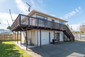 Ein zweistöckiges Haus mit einer überdachten Terrasse, einer Garage und einem eingezäunten Hinterhof.