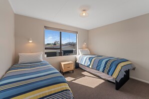 Ein Schlafzimmer mit zwei Betten, einem Fenster und einem kleinen Nachttisch.