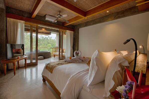 Un dormitorio amplio con una cama grande, televisión y balcón con vistas al exterior.