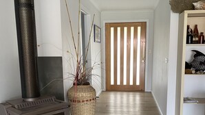 A living room with a wood-burning stove, a large woven basket, and a wooden door in the background.