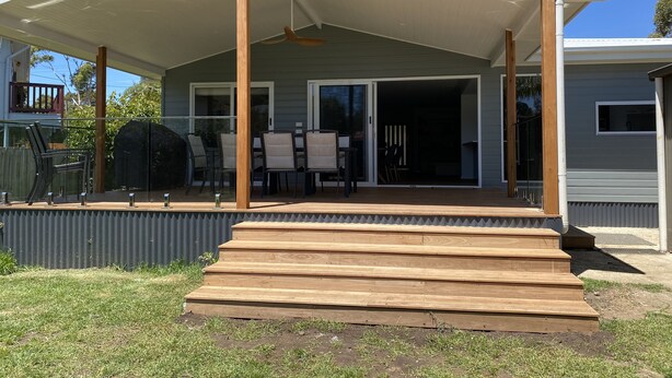 A covered patio with a wooden deck leading to a sliding glass door entrance.