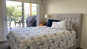 A bedroom with a large bed, a sliding glass door to a patio, and a neutral color scheme.