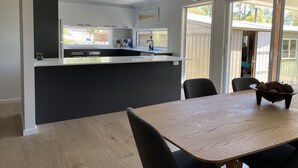 A modern kitchen with white cabinets, a black countertop, and a dining area with a wooden table and chairs.