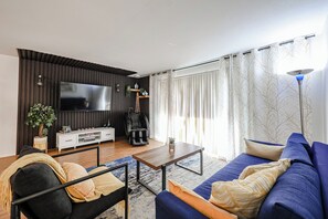 Relax in this stylish living room with a flat-screen TV, comfortable sofa, and cozy armchair.