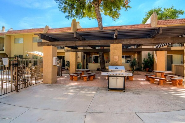 Relax in the shaded patio area, complete with dining tables, comfortable seating, and a barbecue grill.