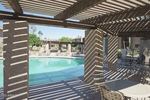 Relax by the serene pool surrounded by a shaded seating area with lounge chairs and a table.