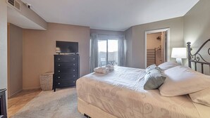 Ein Schlafzimmer mit einem Bett, einem Schminktisch, einem Fernseher und einem Fenster mit Vorhängen.
