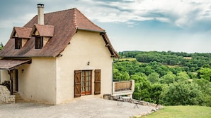 A house with a sloped roof, a chimney, and a balcony with a stone railing. - Fine studio with large terrace and views (Cajarc)
