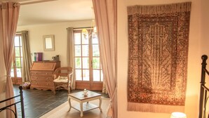 A bedroom with a bed, a nightstand, a chair, a dresser, and a large tapestry. - Fine studio with large terrace and views (Cajarc)