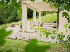 An outdoor patio area with a covered seating arrangement, a table with chairs, and a grill. - Fine studio with large terrace and views (Cajarc)