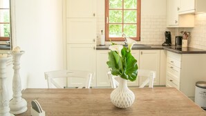 A kitchen with white cabinets, a wooden table, and a vase with flowers. - Fine studio with large terrace and views (Cajarc)