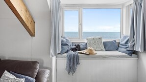 Une pièce chaleureuse avec un coin fenêtre, une poutre en bois et une vue sur la mer.