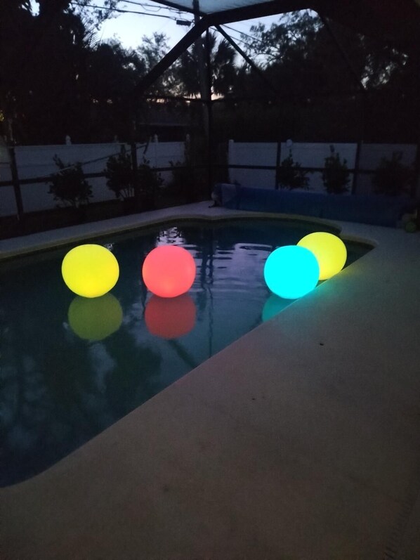 A swimming pool with four illuminated balls in yellow, red, and blue colors.