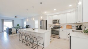 A modern kitchen with white cabinets, stainless steel appliances, and a central island with bar stools. - 2 Blocks to Beach | Ventnor City | Multi- Level Decks | Pet Friendly (Ventnor City)