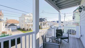 A covered balcony with a view of neighboring houses, a white railing, and a small table with chairs. - 2 Blocks to Beach | Ventnor City | Multi- Level Decks | Pet Friendly (Ventnor City)