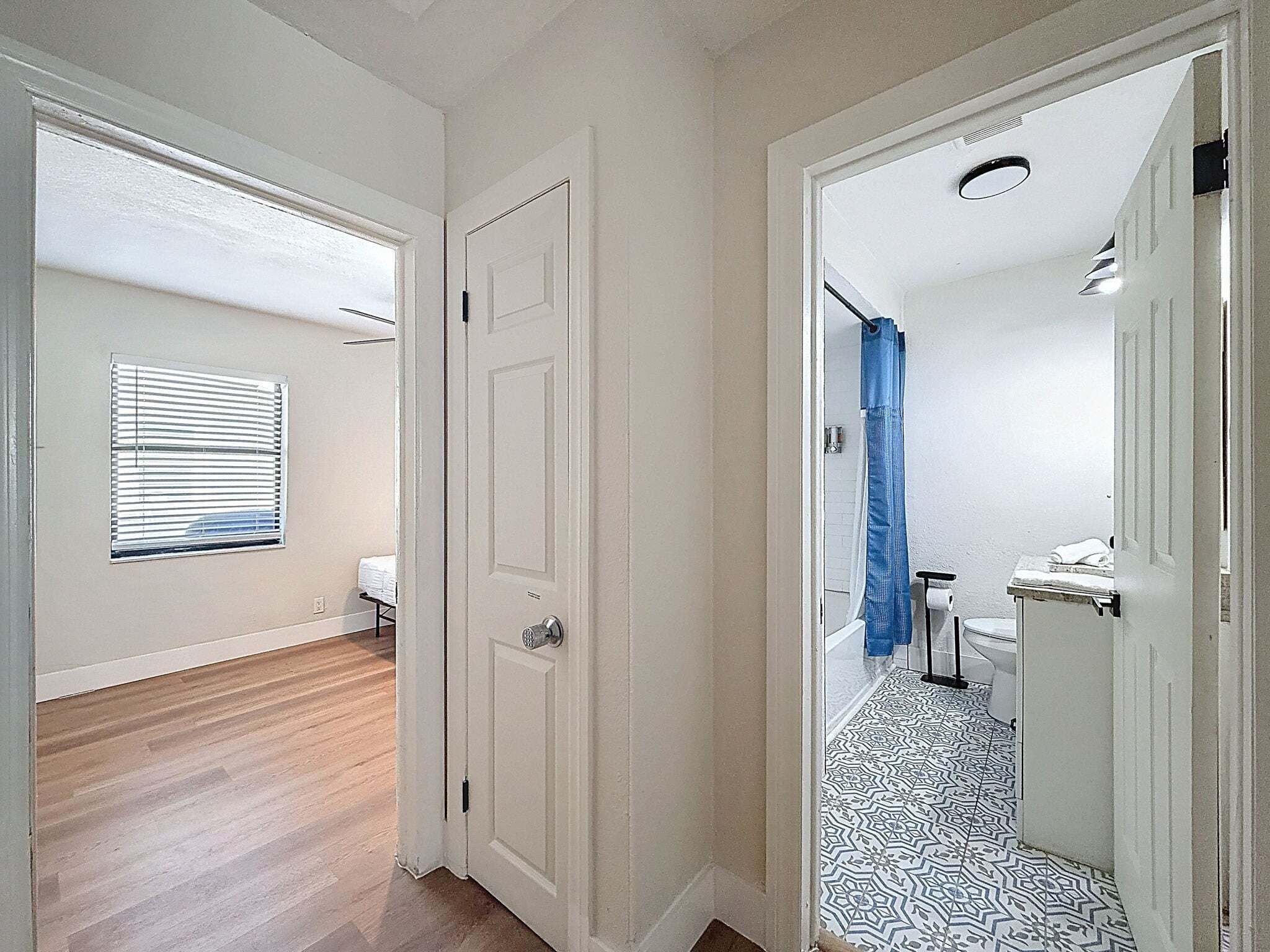 Um corredor com uma porta que dá para um banheiro com chuveiro e vaso sanitário.