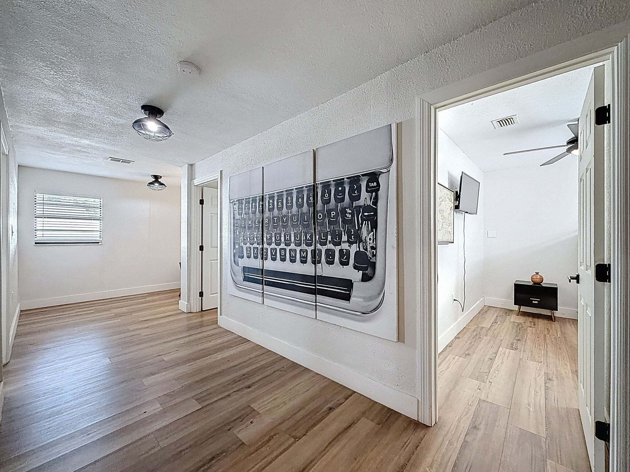 Ein geräumiger Flur mit Holzboden, Deckenventilator und Wandleuchte.