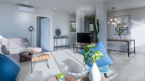A modern living room with a sofa, coffee table, and a dining area with chairs and a TV. - Lovely and luxury apartment in Altea, Costa Blanca, Spain for 6 persons (Altea)