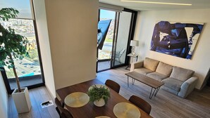 A modern living room with a dining area, large windows, and a view of the city.