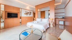 Une chambre d’hôtel moderne dotée d’un grand lit, d’un téléviseur à écran plat, d’une table basse en verre et d’une petite kitchenette.