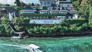 Un complexe hôtelier comprenant plusieurs bâtiments, une piscine et un bateau amarré au bord de l’eau.