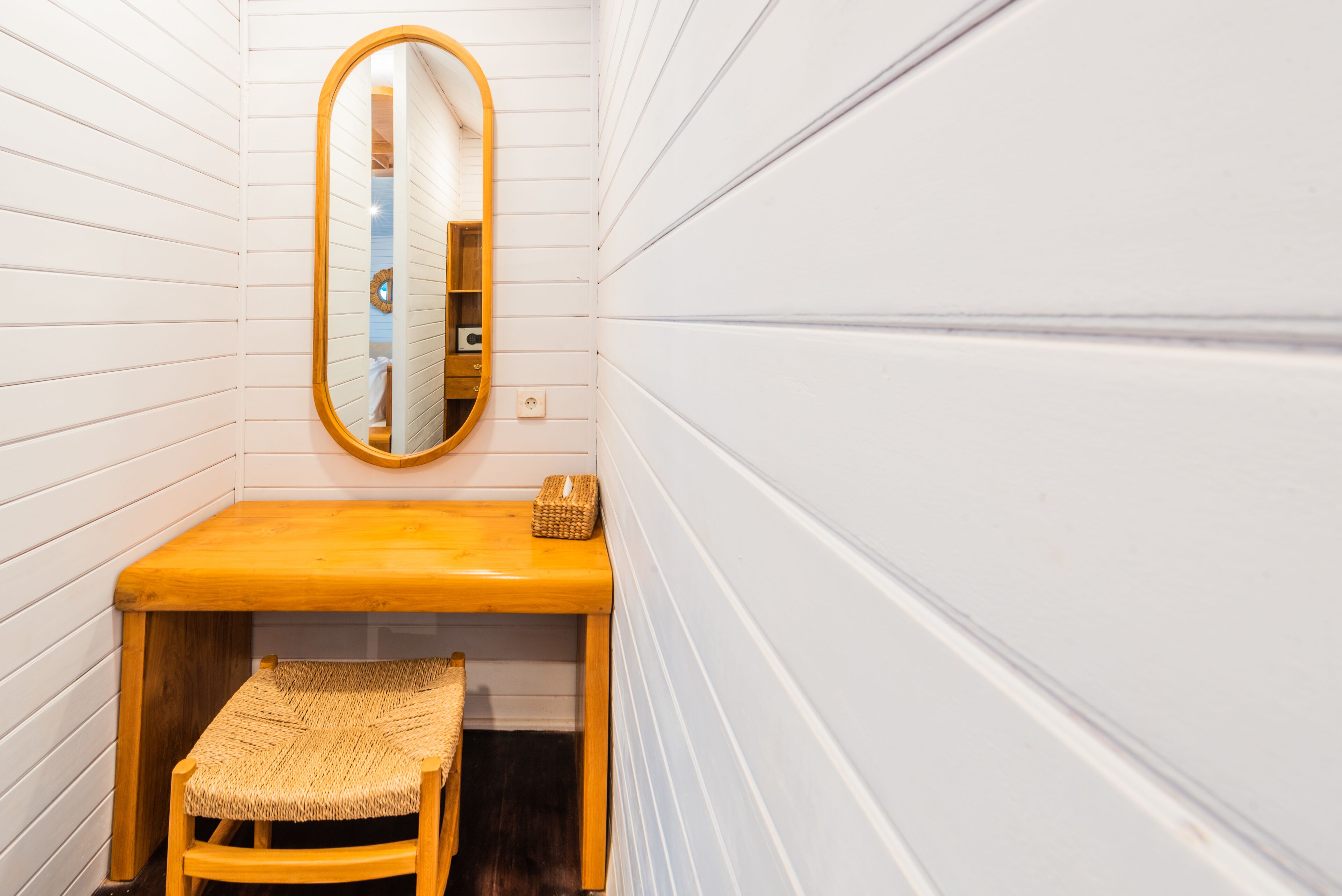 A small bathroom with a wooden bench, a mirror, and a shelf.